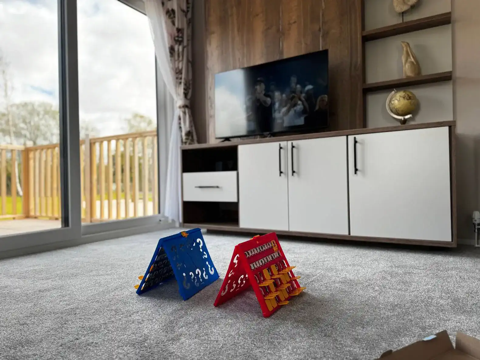 Colorful board games on carpet in a cozy living room with a TV and wooden decor