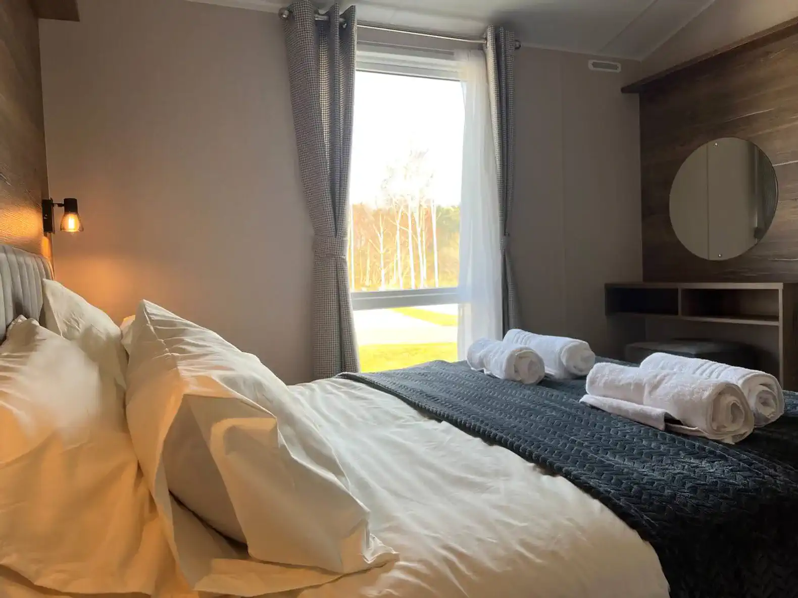 Cozy bedroom with a large window and neatly arranged towels on the bed
