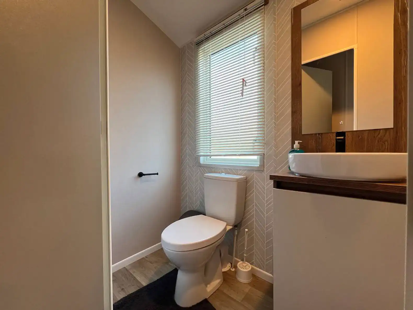 Modern bathroom featuring a toilet, sink, and natural light from a window