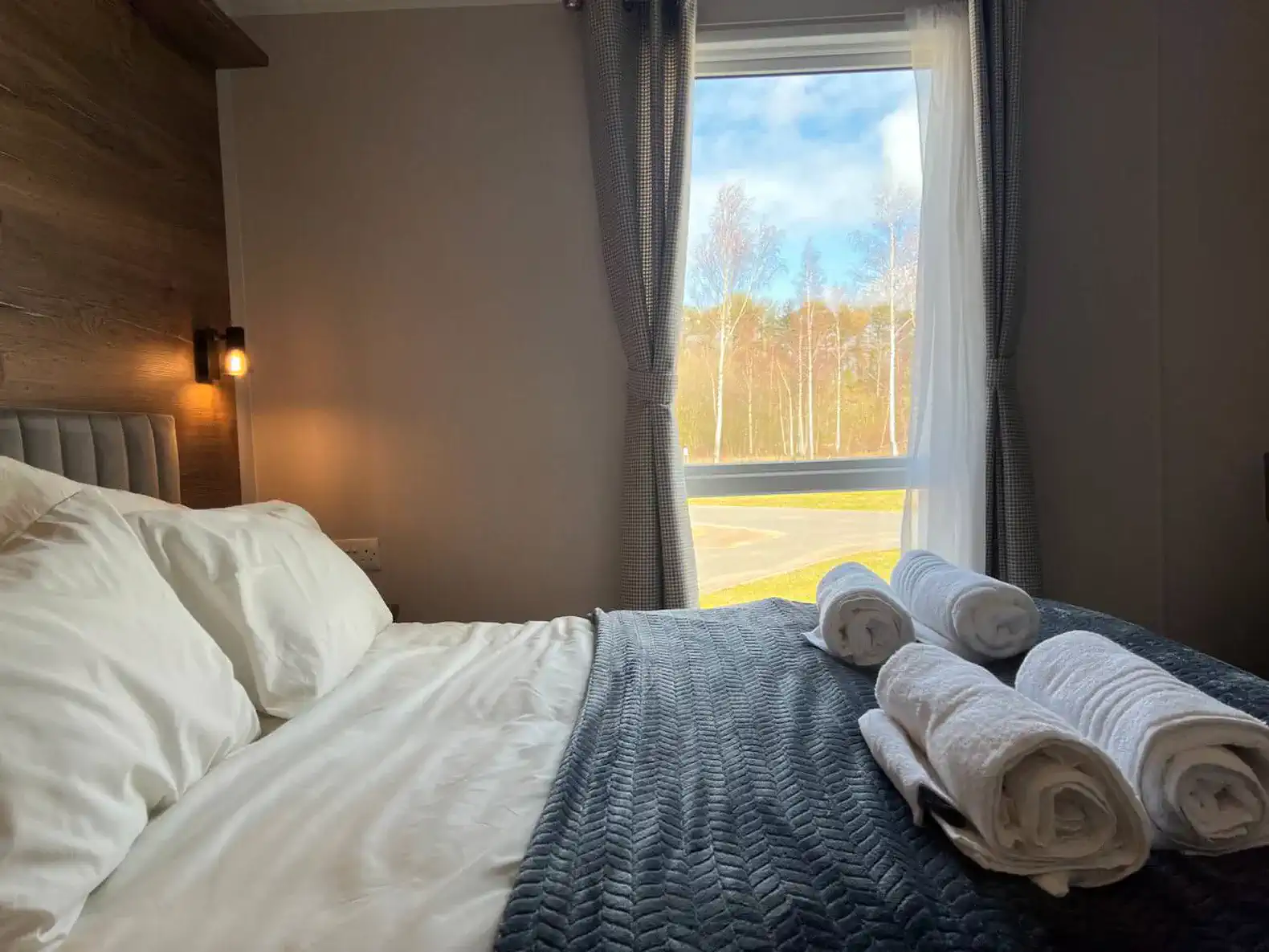 Cozy master bedroom with neatly arranged towels and a view of trees outside