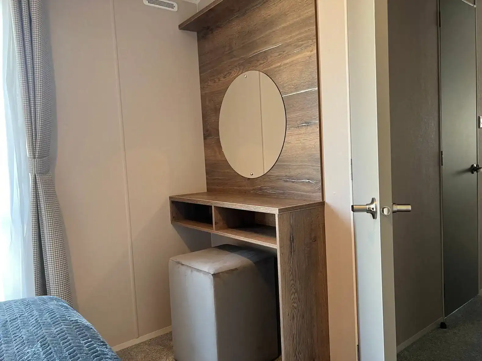 Wooden vanity with round mirror and stool in a cozy bedroom