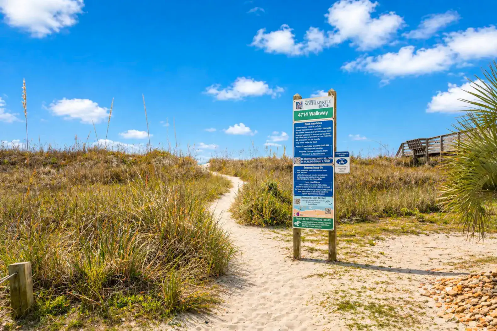 Pathway leading to the beach with a sign and grassy surroundings