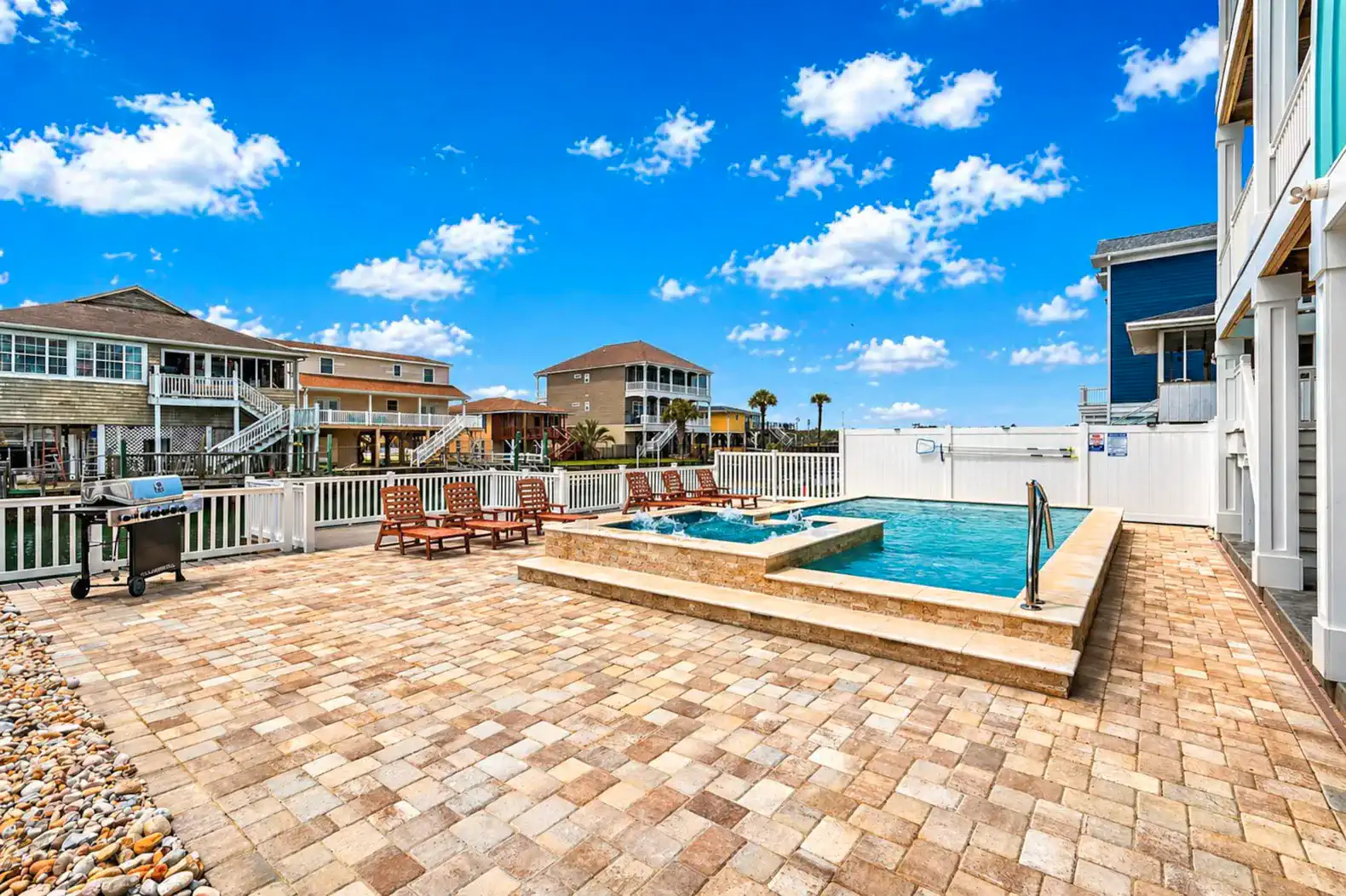 Spacious outdoor area featuring a pool, hot tub, and seating with a view of nearby houses