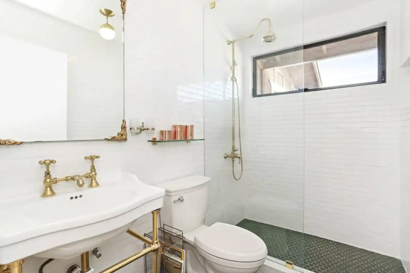 Elegant bathroom with gold fixtures, glass shower, and white subway tiles