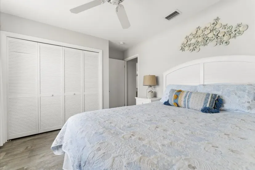 Cozy master bedroom with a blue quilt, decorative pillows, and ample closet space