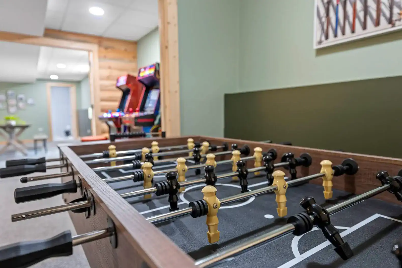 Foosball table in a game room with arcade machines in the background