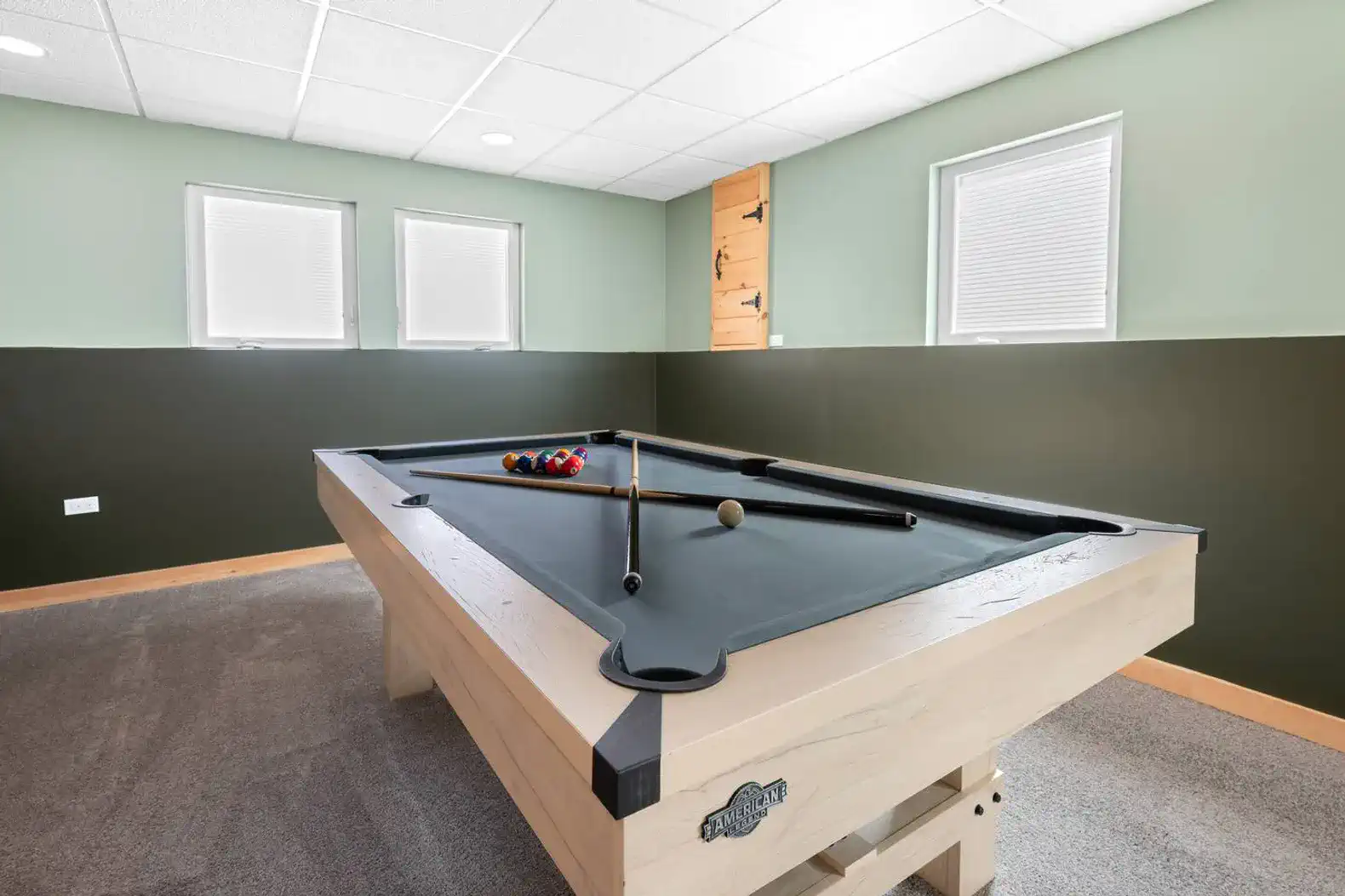 Interior view of a game room featuring a pool table and natural light from windows