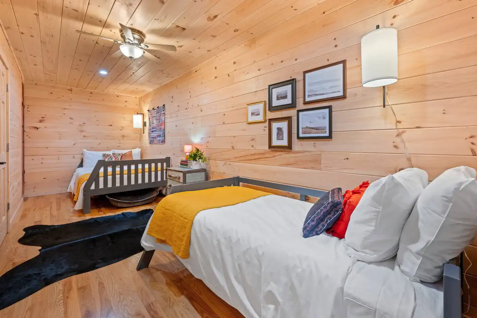 Cozy guest bedroom with two beds, wooden walls, and decorative artwork