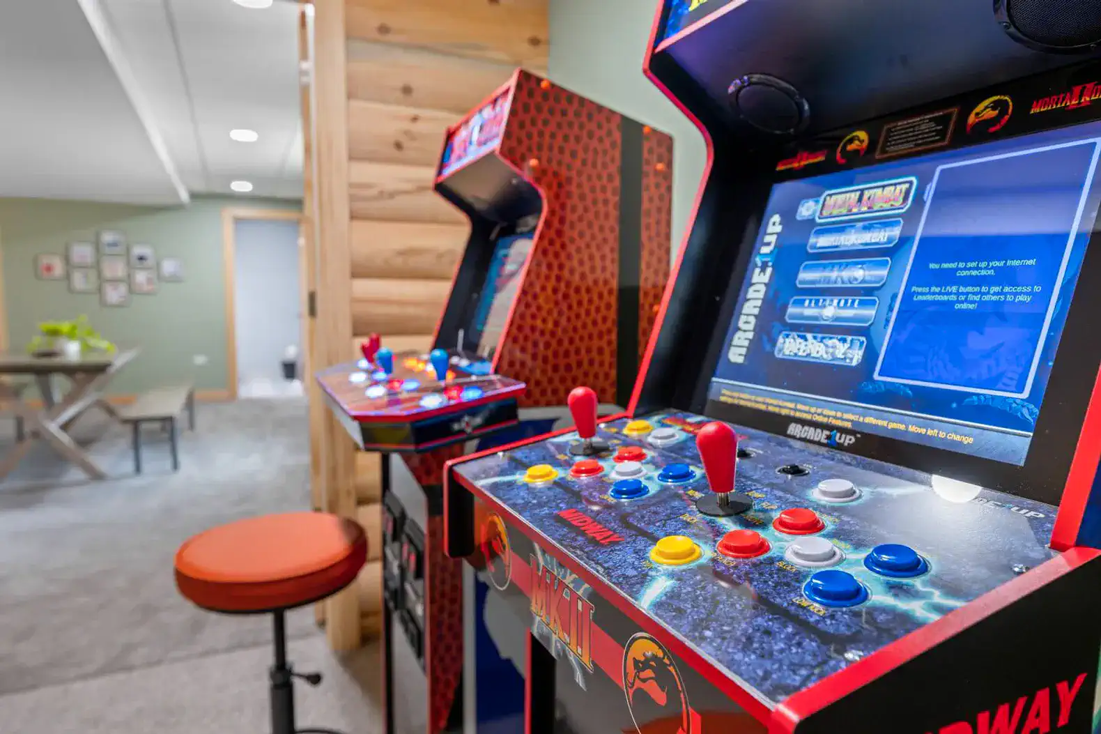 Two arcade game machines with colorful controls in a cozy game room