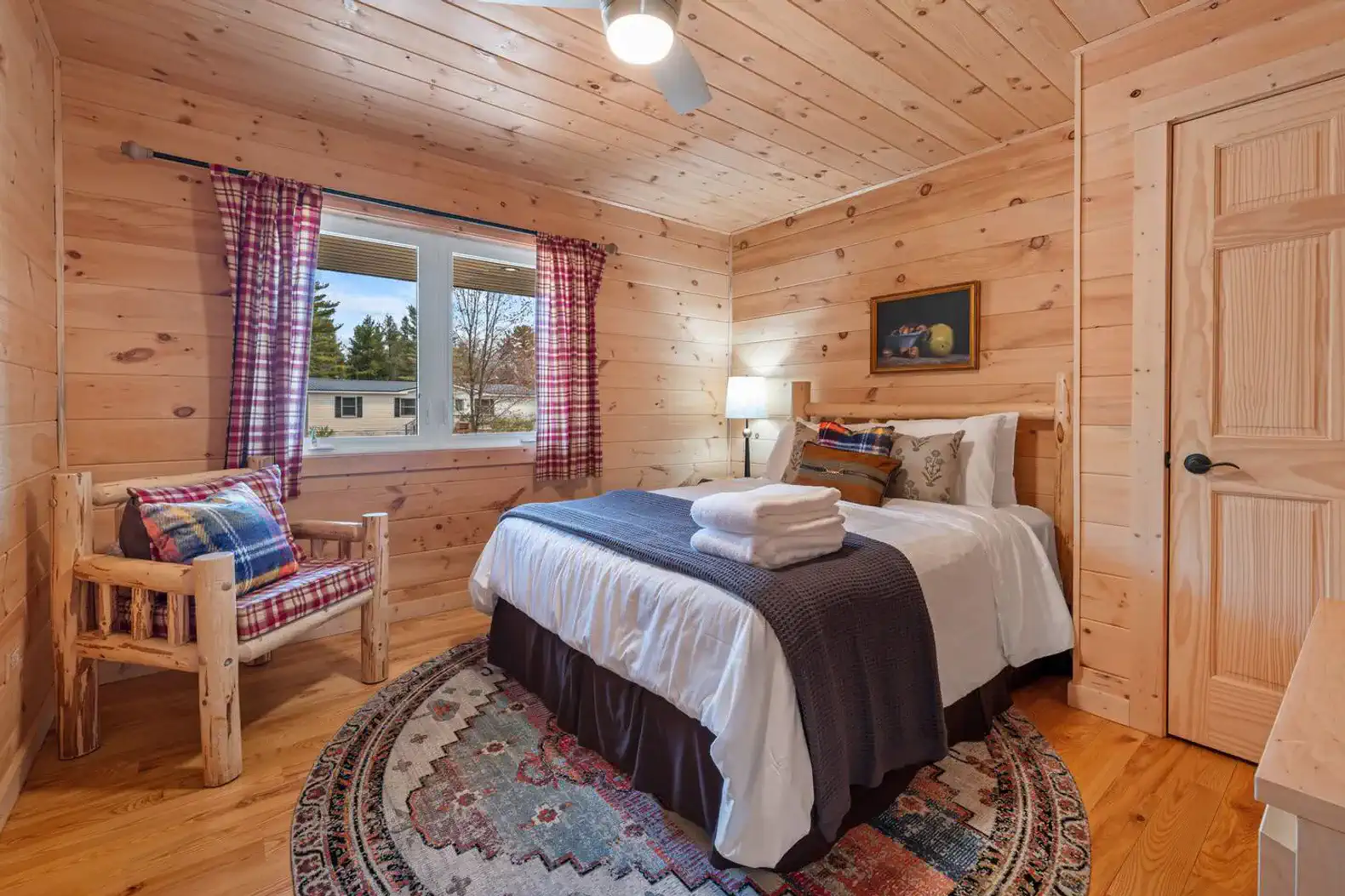 Cozy guest bedroom with wooden walls, a bed, and a comfortable chair