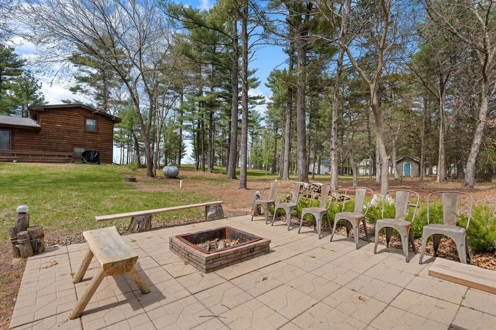 Outdoor fire pit area surrounded by seating and trees