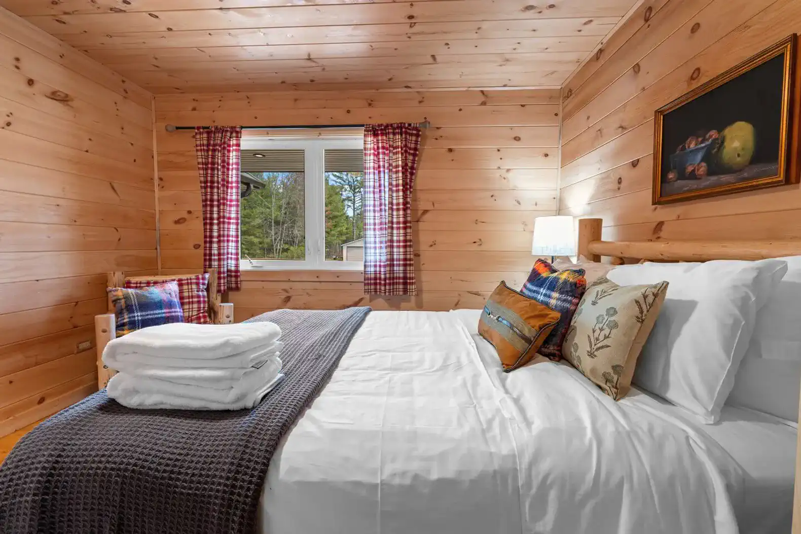 Cozy bedroom with wooden walls, a large bed, and natural light from the window