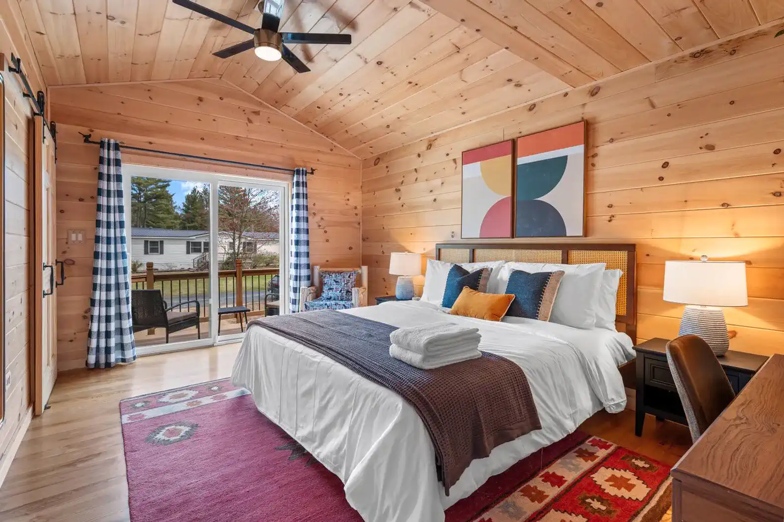 Cozy master bedroom with wooden walls, large bed, and access to a deck