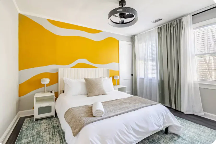 Comfortable bedroom with a queen bed, bold mural accent wall, and natural light pouring in. Your peaceful escape after a day of exploring.