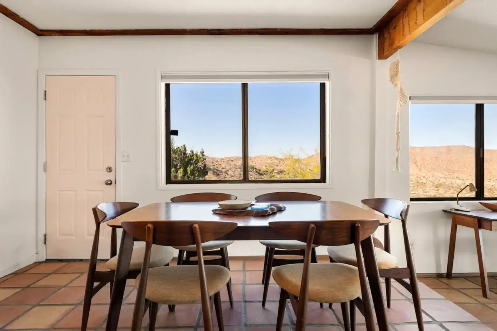 Bright dining area with wooden table and chairs, featuring scenic mountain views through large windows