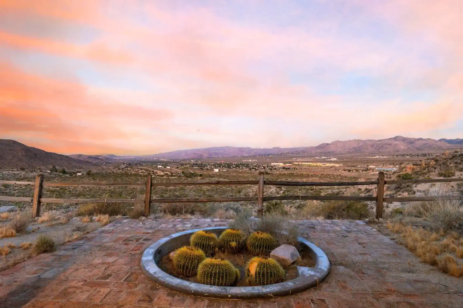 Desert landscape with cacti and mountains under a colorful sunset sky