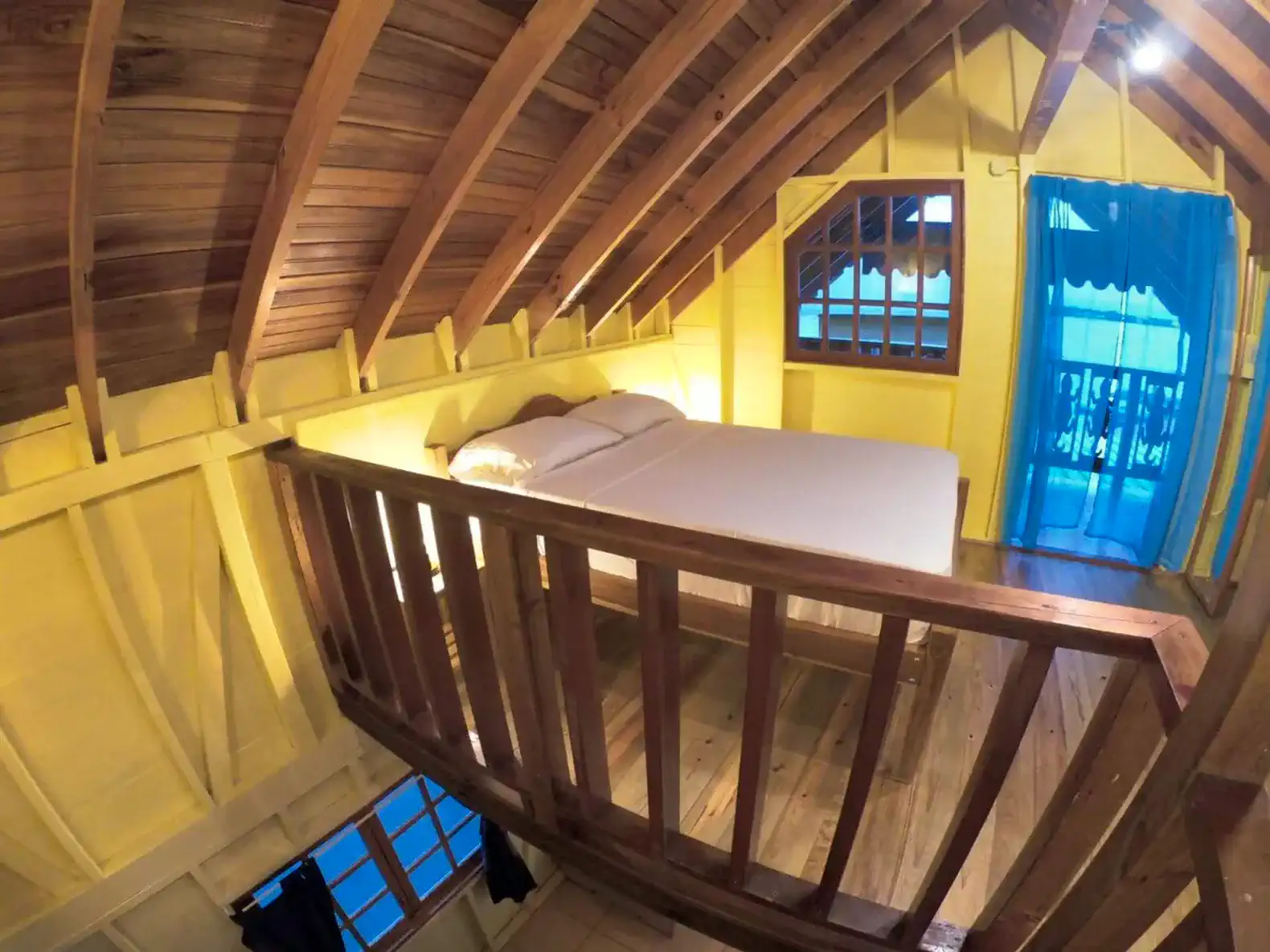 Cozy loft bedroom with wooden beams and bright yellow walls