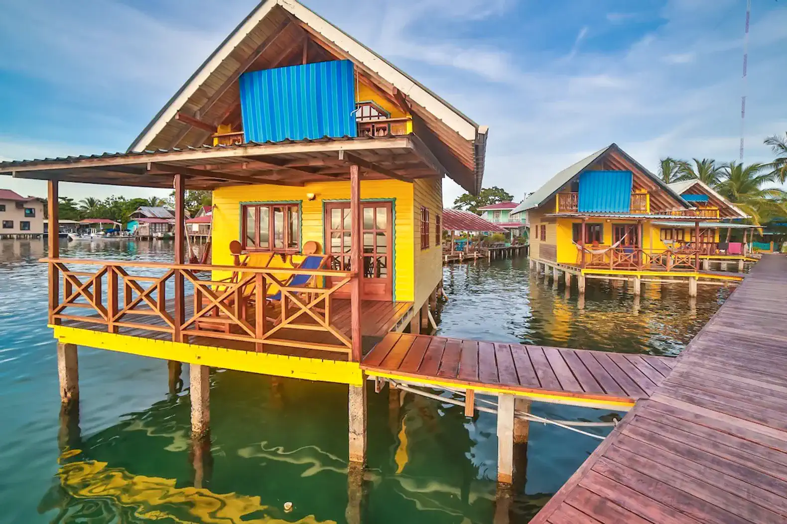 Colorful bungalow on stilts with a wooden deck overlooking the water