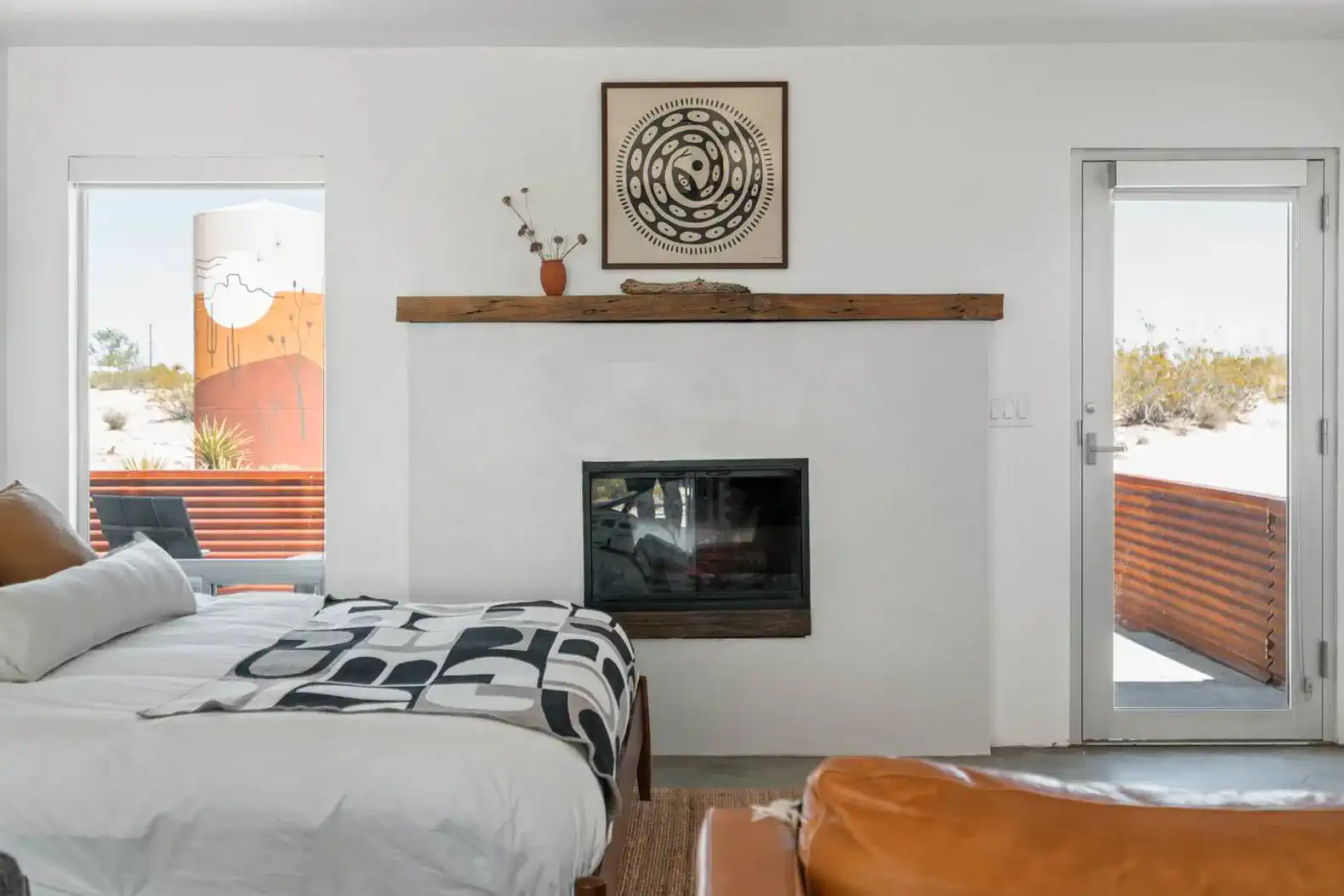 Cozy master bedroom with a fireplace and large windows showcasing desert views