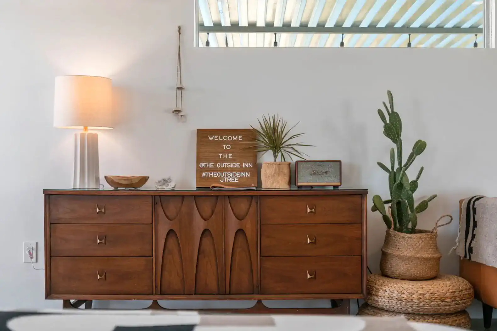 Stylish wooden dresser with decorative items and a lamp in a cozy living space