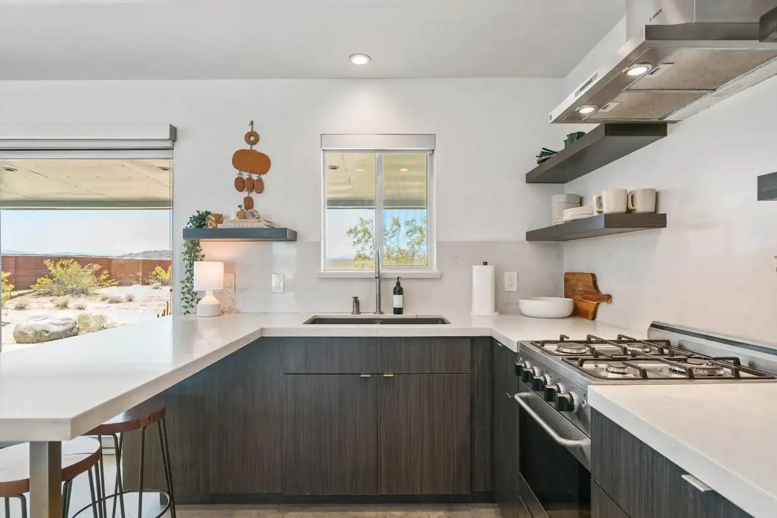 Modern kitchen with sleek countertops, gas stove, and open shelving