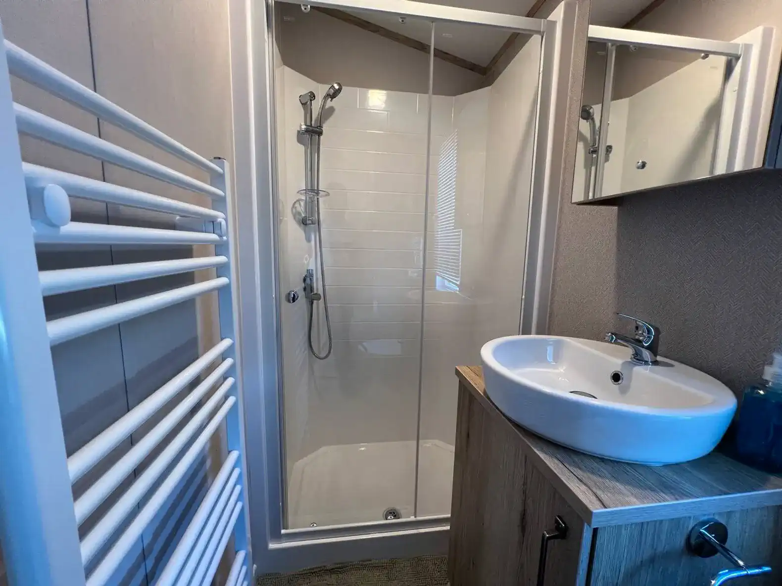 Modern bathroom featuring a glass shower, sink, and towel radiator