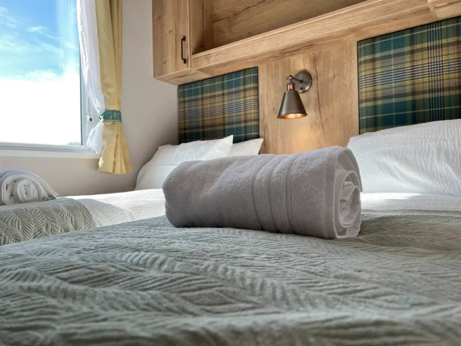 Cozy guest bedroom with two beds and a rolled towel on the cover
