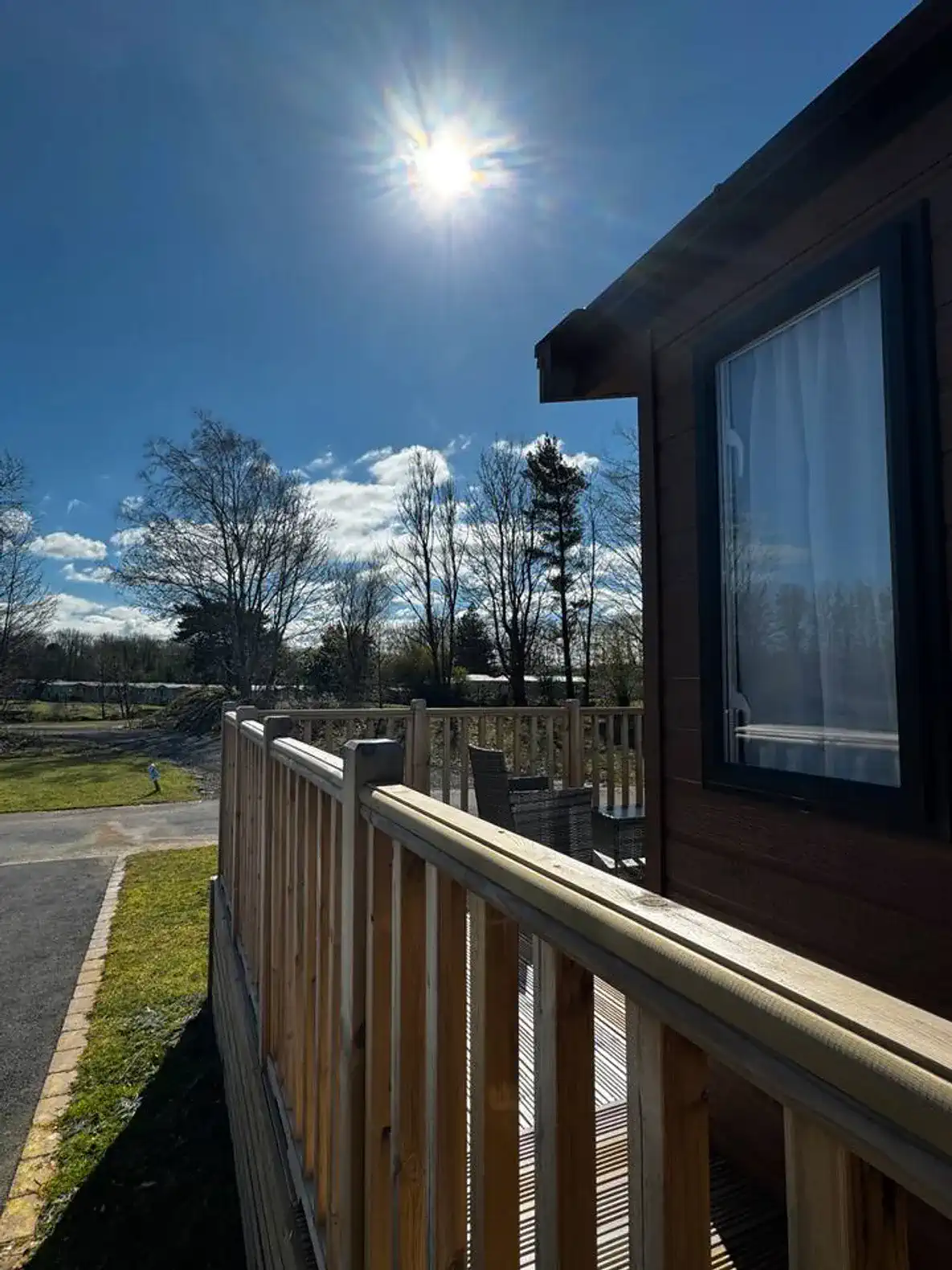 Sunny outdoor deck with wooden railing and views of trees