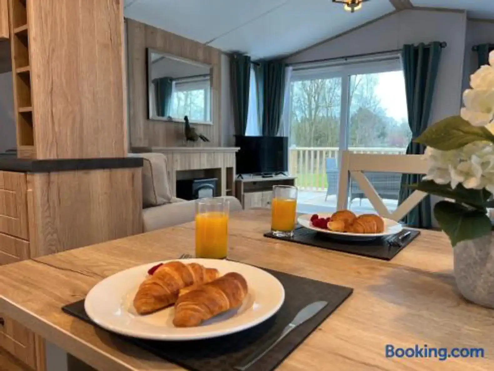 Dining table set with croissants and juice, cozy living area in the background