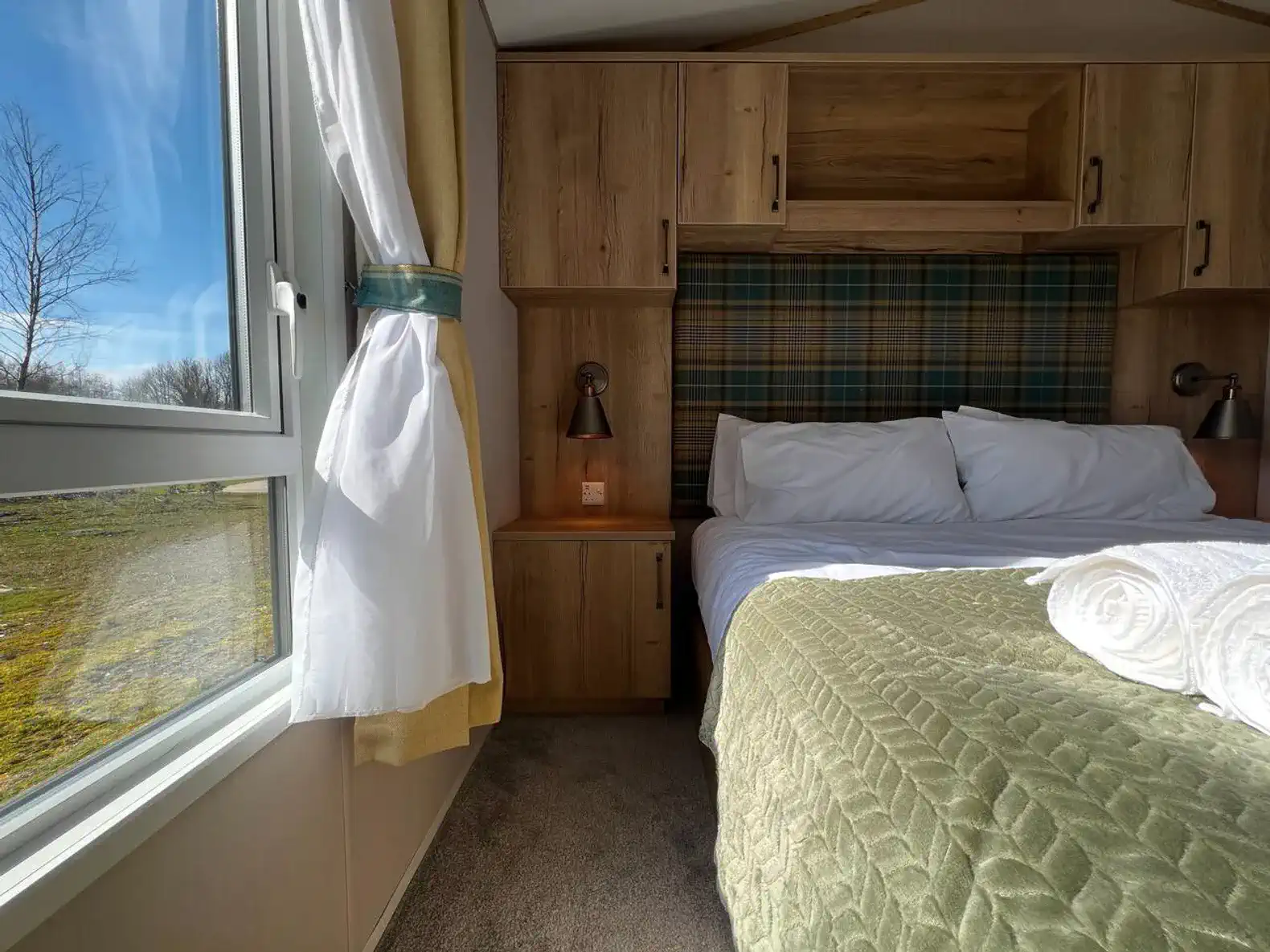 Cozy master bedroom with plaid headboard and natural light from window