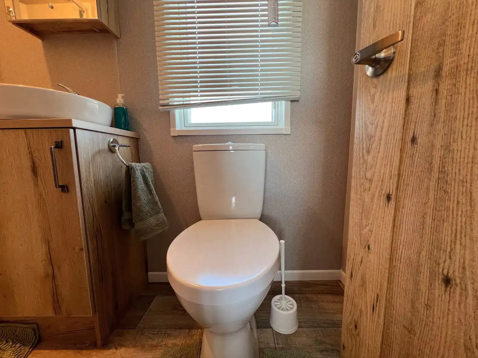 Modern bathroom with a toilet and sink featuring wooden accents