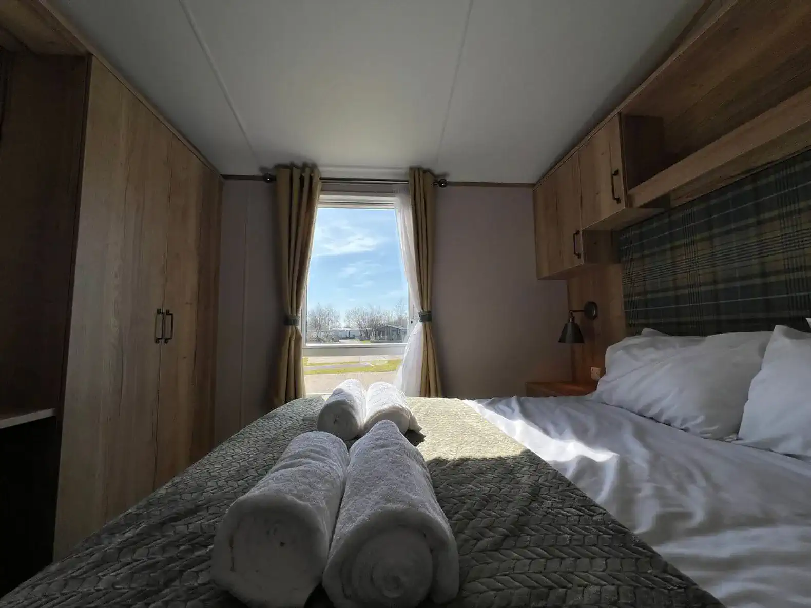 Cozy bedroom with a view featuring a neatly made bed and rolled towels