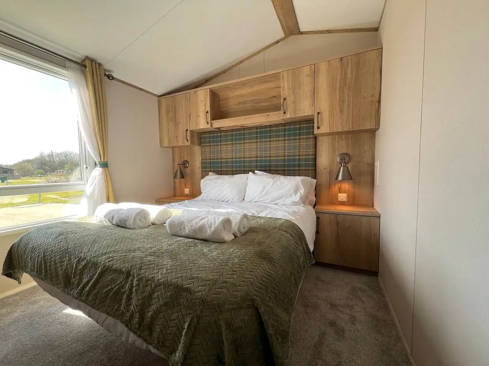 Cozy master bedroom with a large bed, wooden accents, and natural light from a window