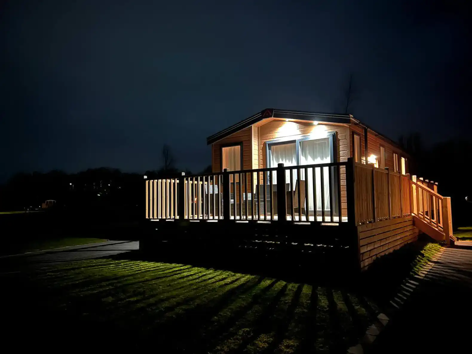 Cozy exterior view of the property illuminated at night with a wooden deck