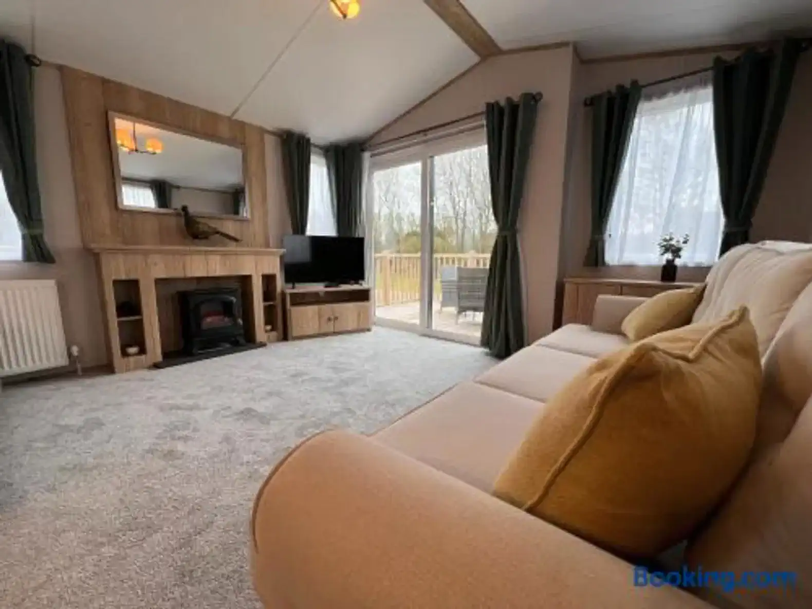 Cozy living room with a sofa, TV, and large windows leading to a deck
