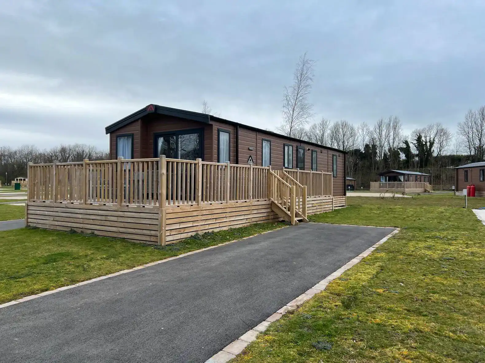 Exterior view of a modern cabin with a wooden deck and landscaped lawn