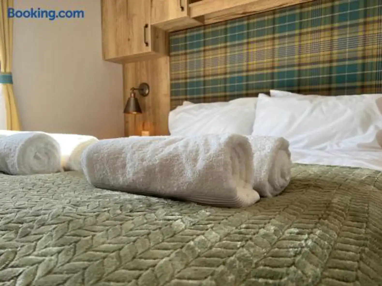 Cozy master bedroom with neatly arranged towels on a green quilted bedspread