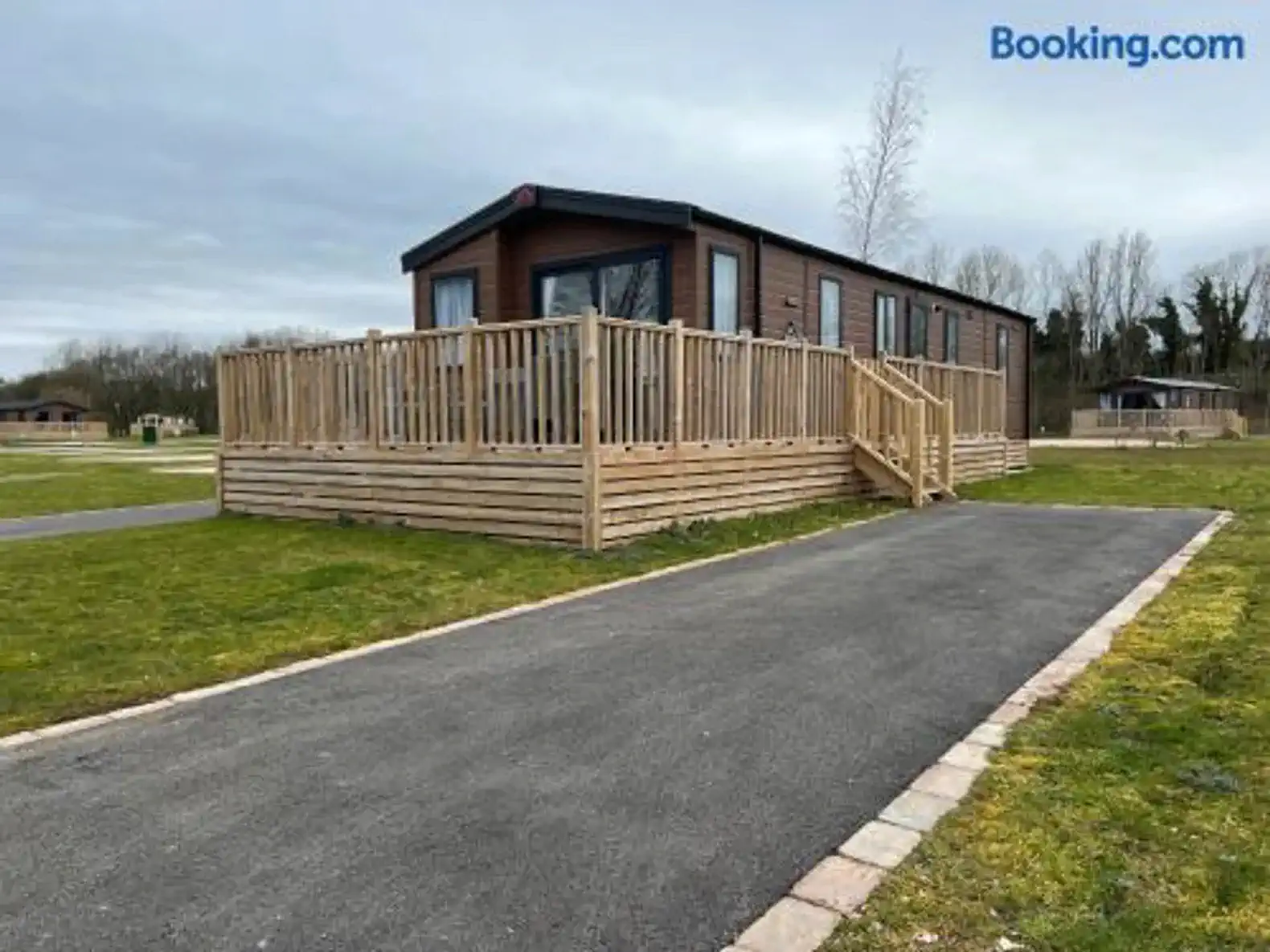 Exterior view of a wooden cabin with a large deck and grassy area
