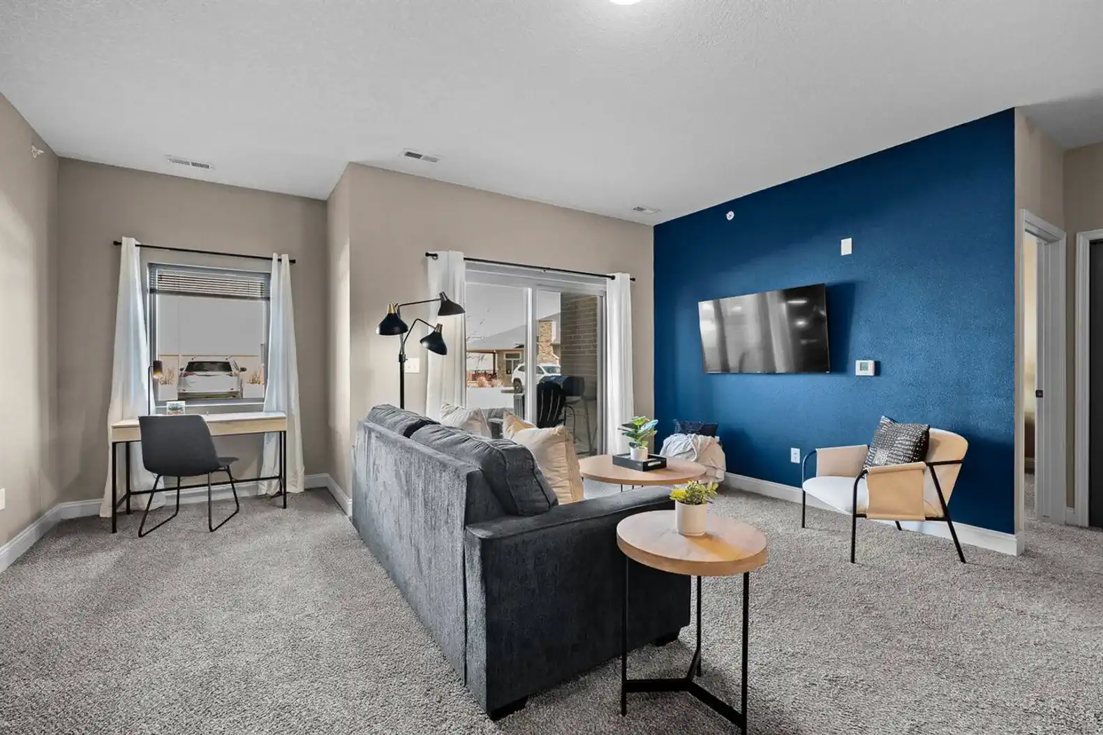Bright, open living area with a comfortable layout for relaxing or working—featuring a cozy seating area, dedicated workspace, and direct access to the private patio for easy indoor-outdoor living.