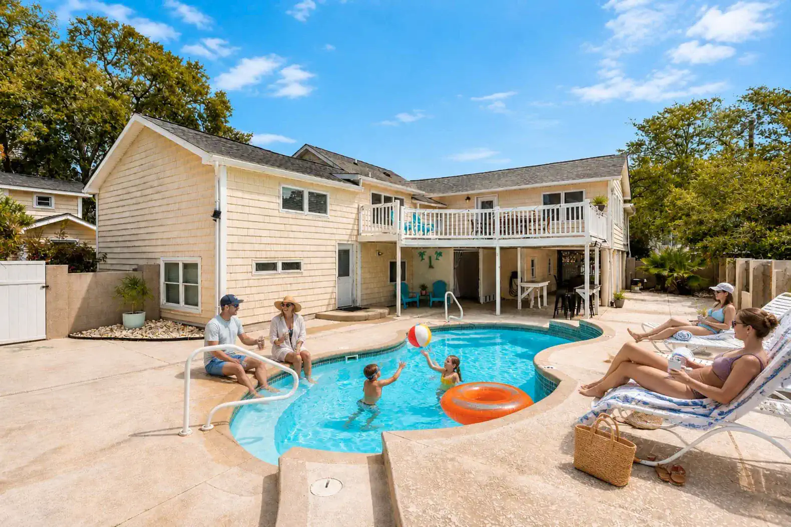 Family enjoying the pool with beach balls and floats in a sunny outdoor area