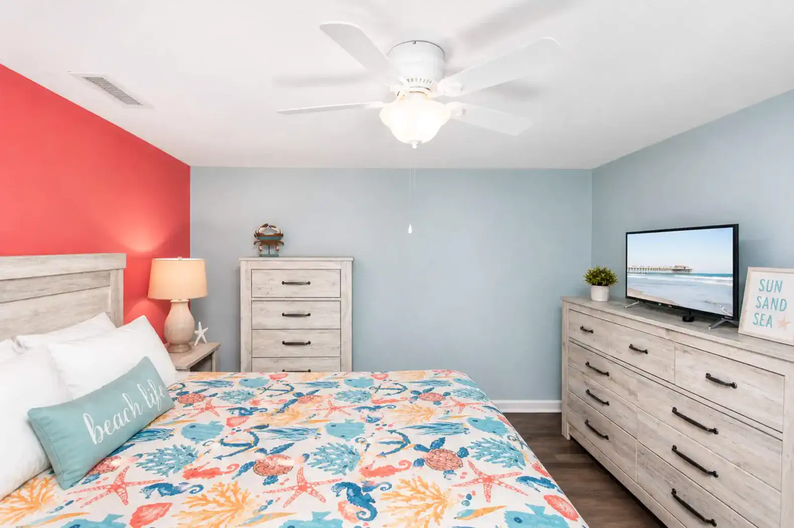 Brightly decorated guest bedroom with colorful bedding and a TV