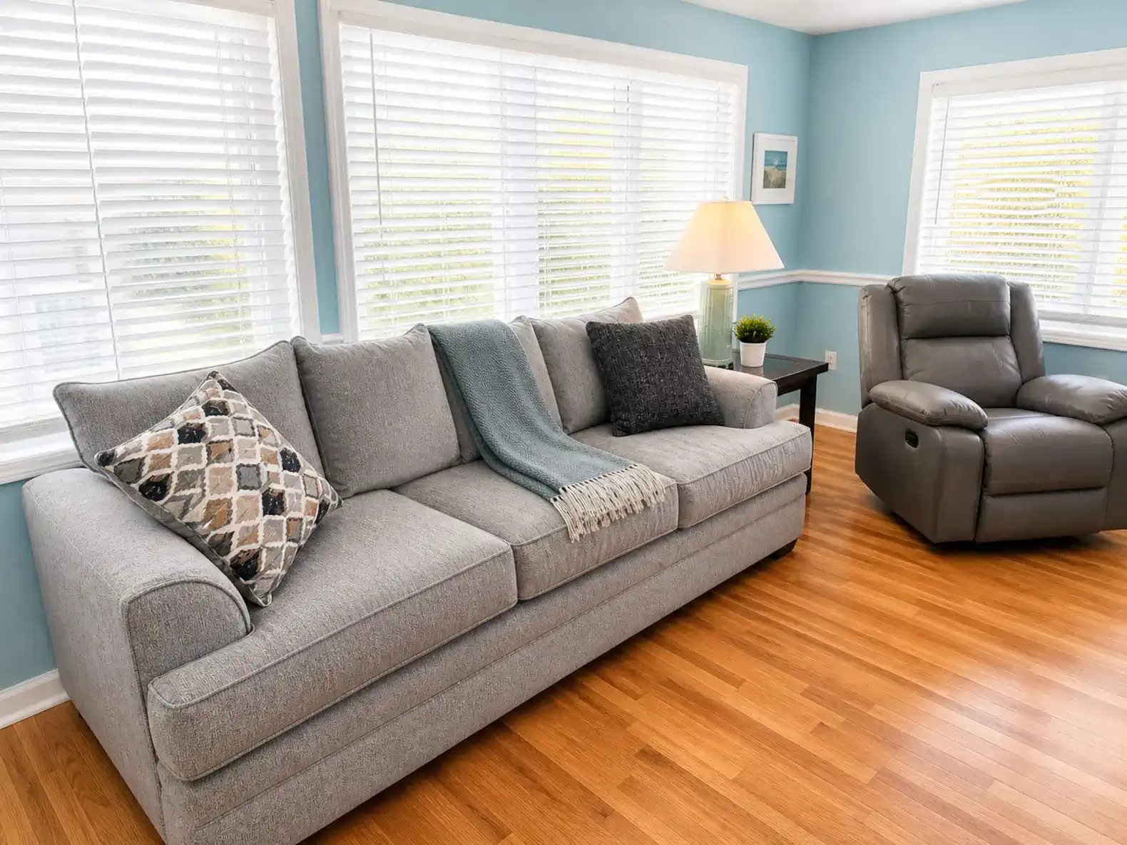 Cozy living room with a gray sofa, decorative pillows, and large windows letting in natural light
