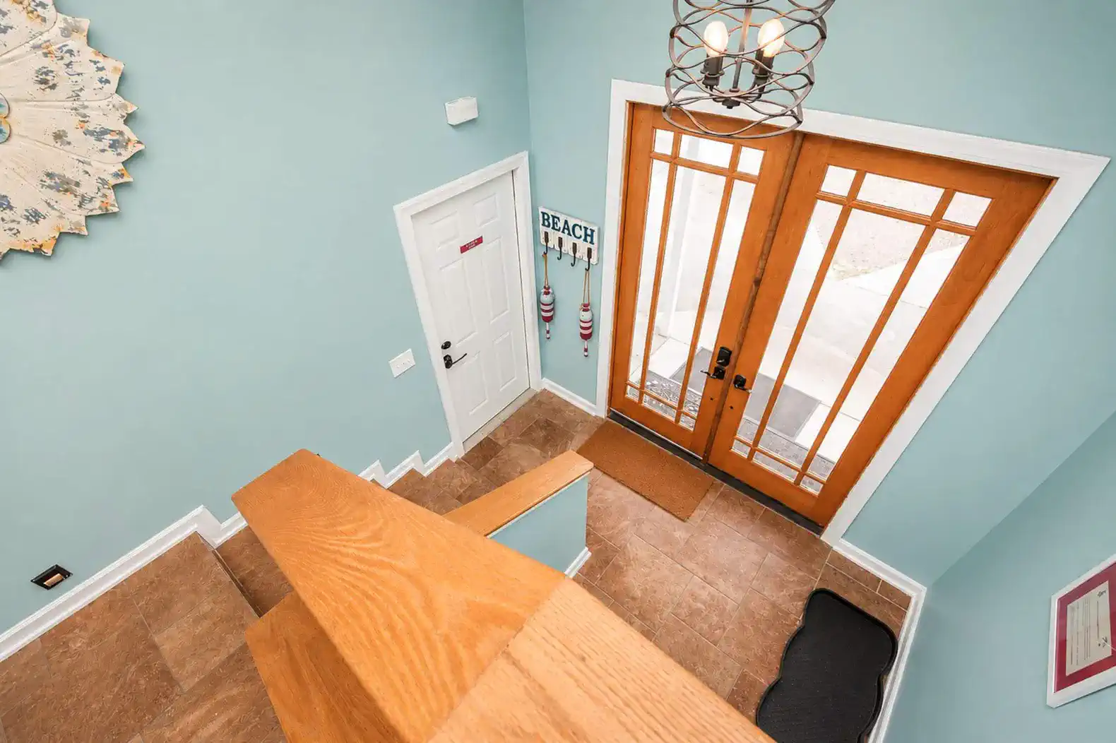 Bright foyer with blue walls and wooden double doors leading outside