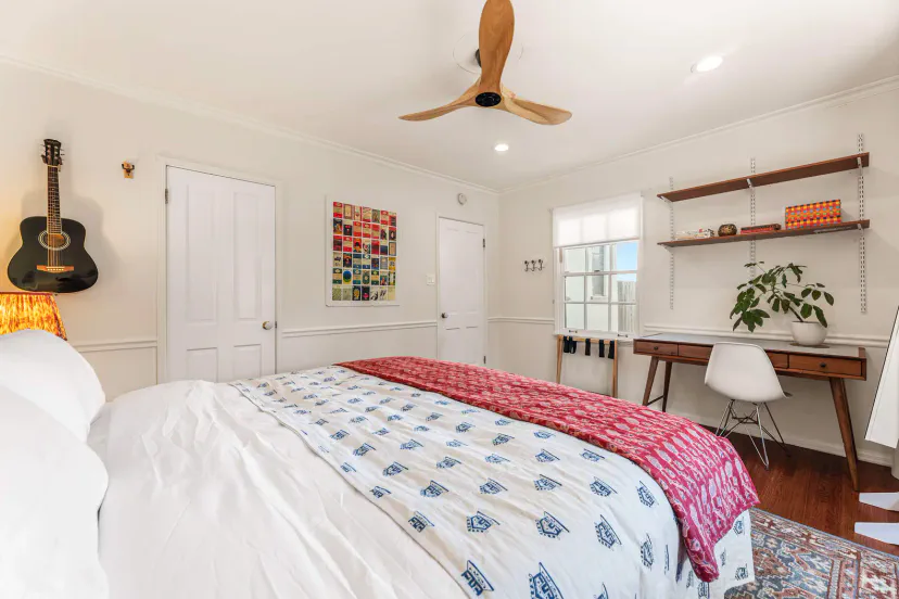 Comfortable King guest bedroom with desk, window seat, closet, storage and ceiling fan