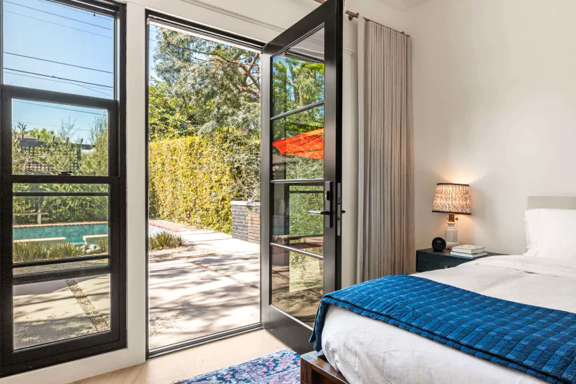 Des portes-fenêtres s'ouvrant depuis la suite principale vers l'arrière-cour privée, créant une vie intérieure-extérieur sans couture dans cette maison de Valley Village.