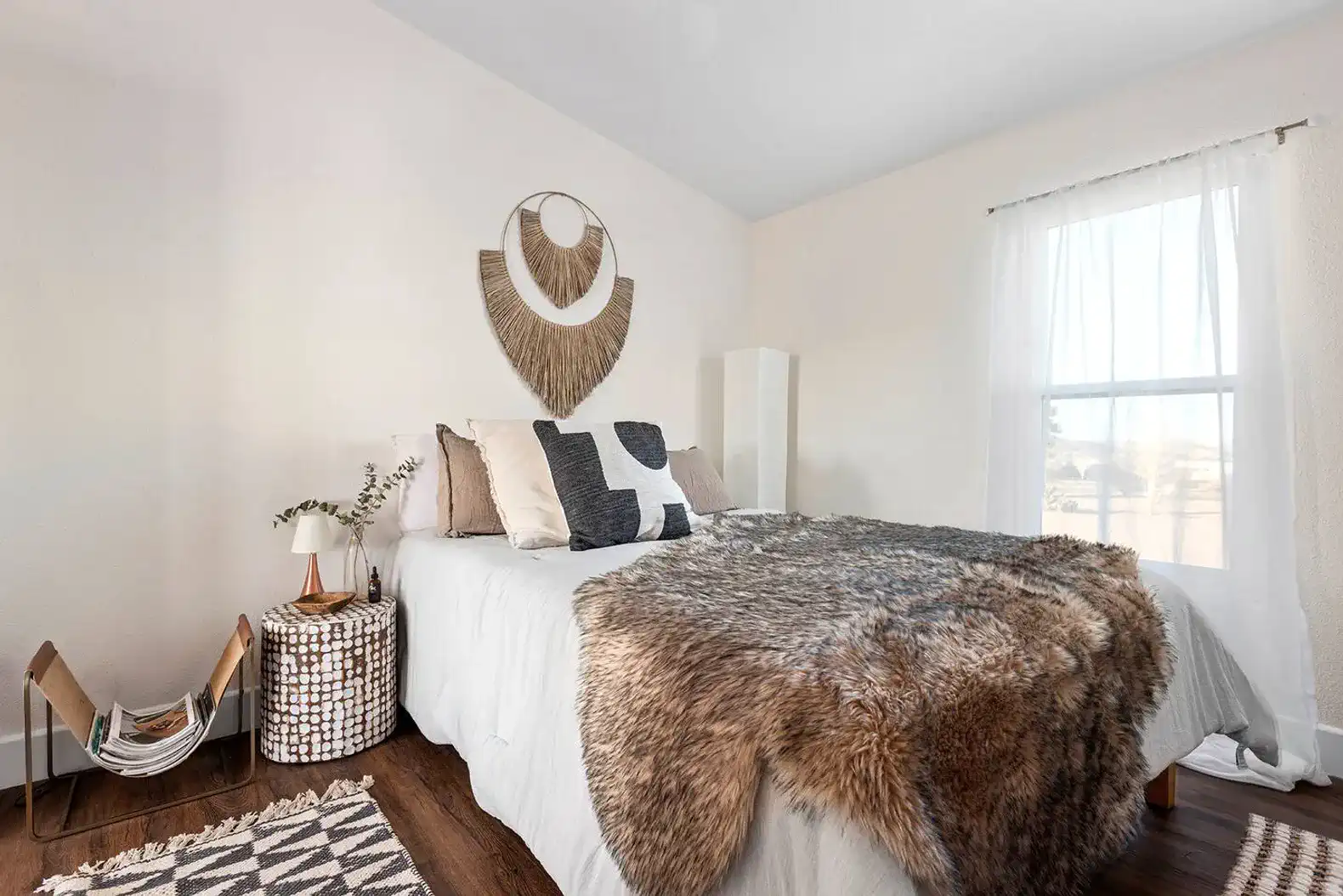 Cozy guest bedroom with a plush bed, decorative wall art, and natural light