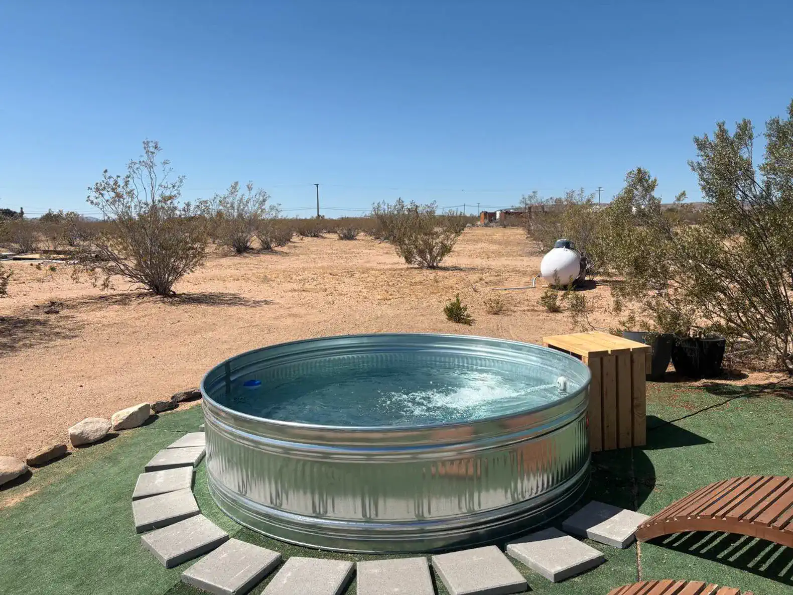 Outdoor hot tub surrounded by desert landscape and shrubs