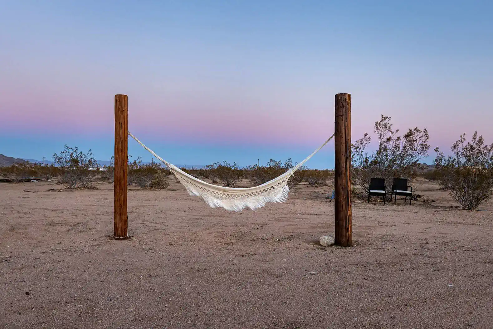 Hammock suspended between two wooden posts in a desert landscape
