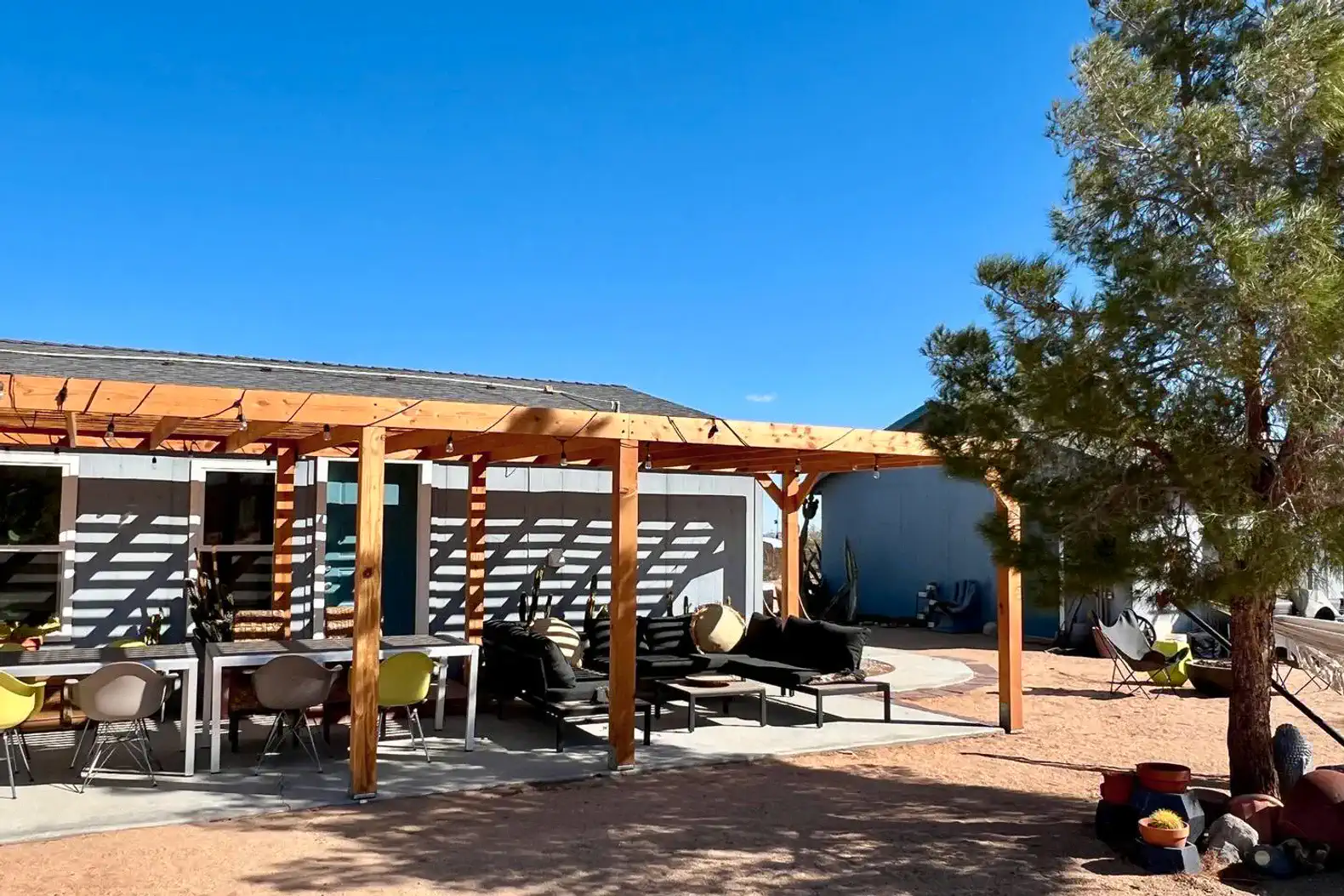 Outdoor patio area with seating and dining table under a wooden pergola