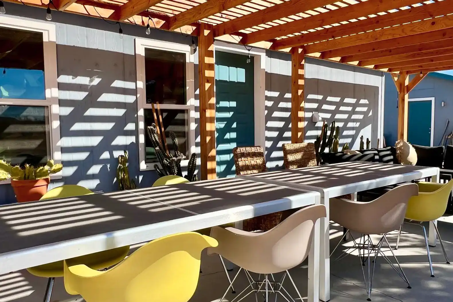 Spacious outdoor dining area with colorful chairs under a wooden pergola